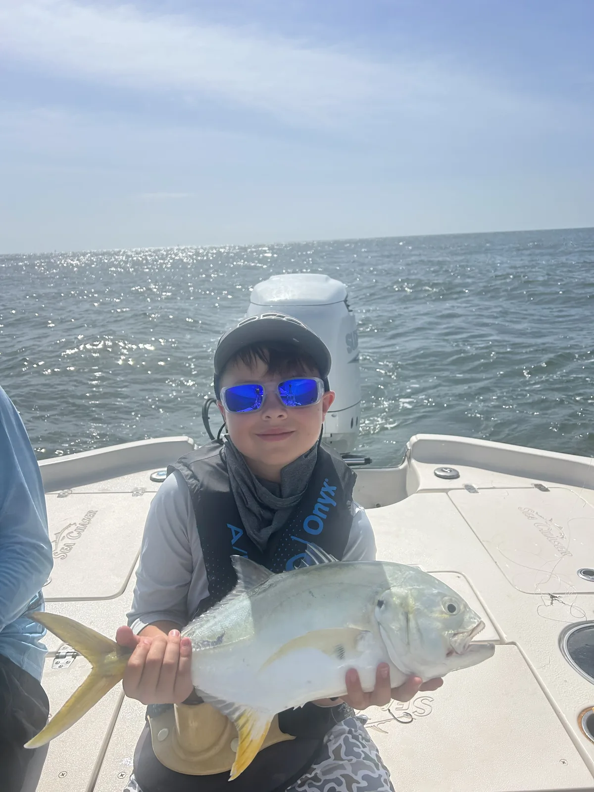 A camper holds a silvery fish aboard a fishing boat.