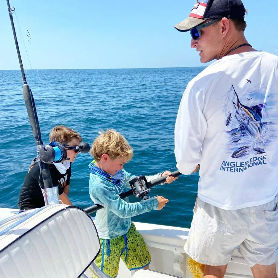 A captain helps young anglers fish from a charter boat.