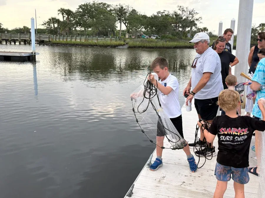 Campers watch a hands-on cast-net lesson at a dock.