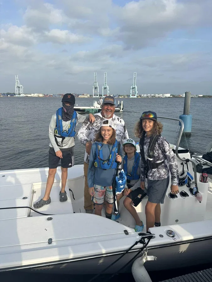 Young anglers and a captain gather aboard a charter fishing boat.