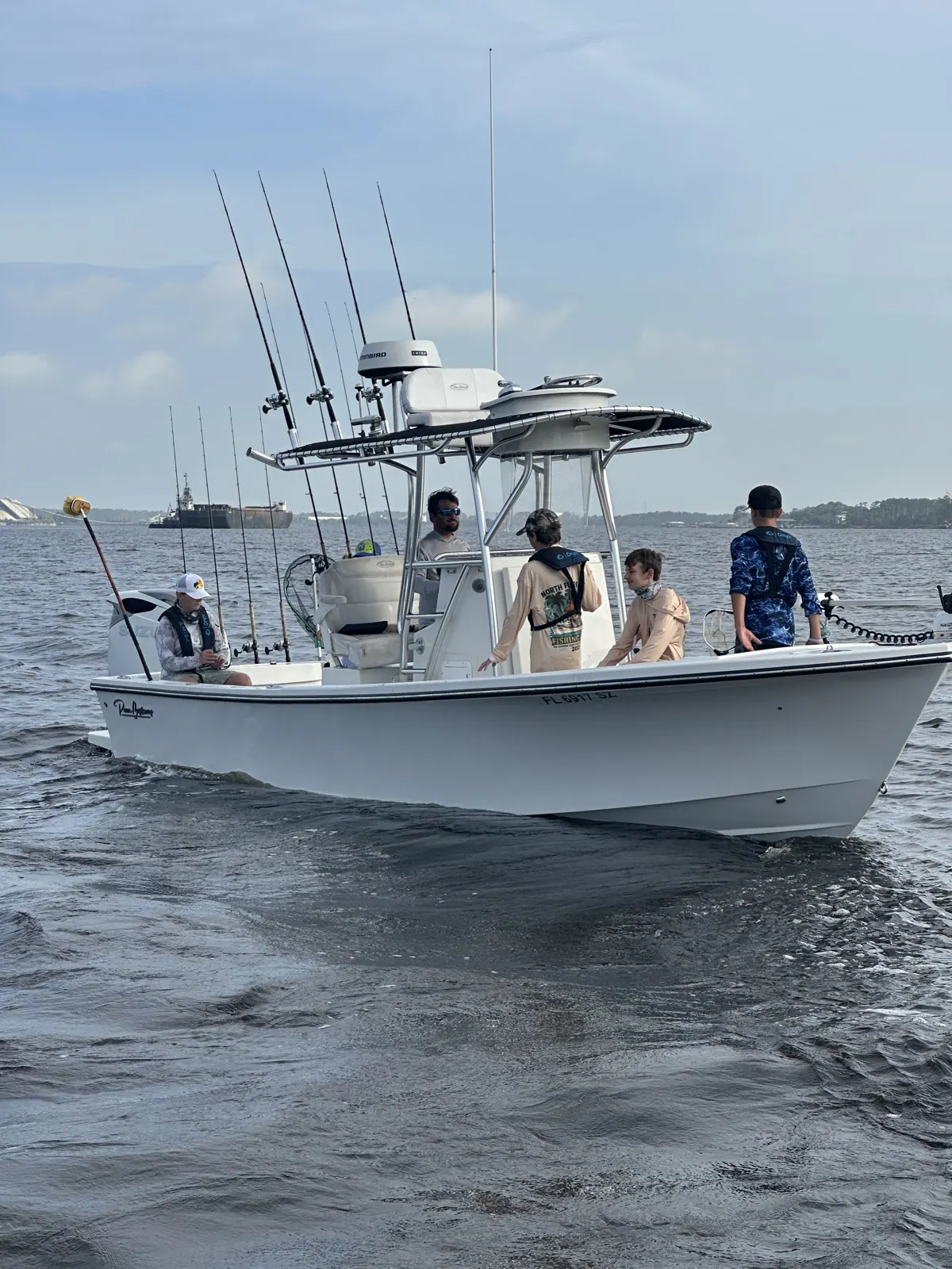 Campers and an adult aboard a fishing boat on the water.