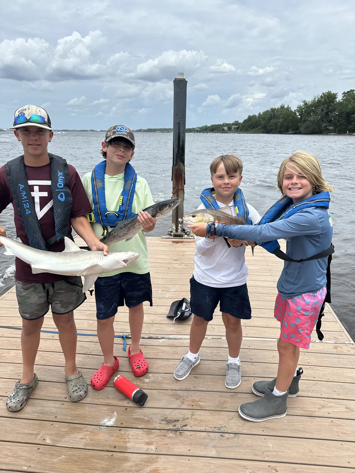 Four campers pose together with fish on a dock.