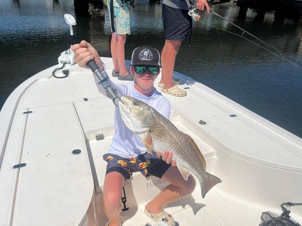 Camper on the bow of a charter boat holding a bull redfish