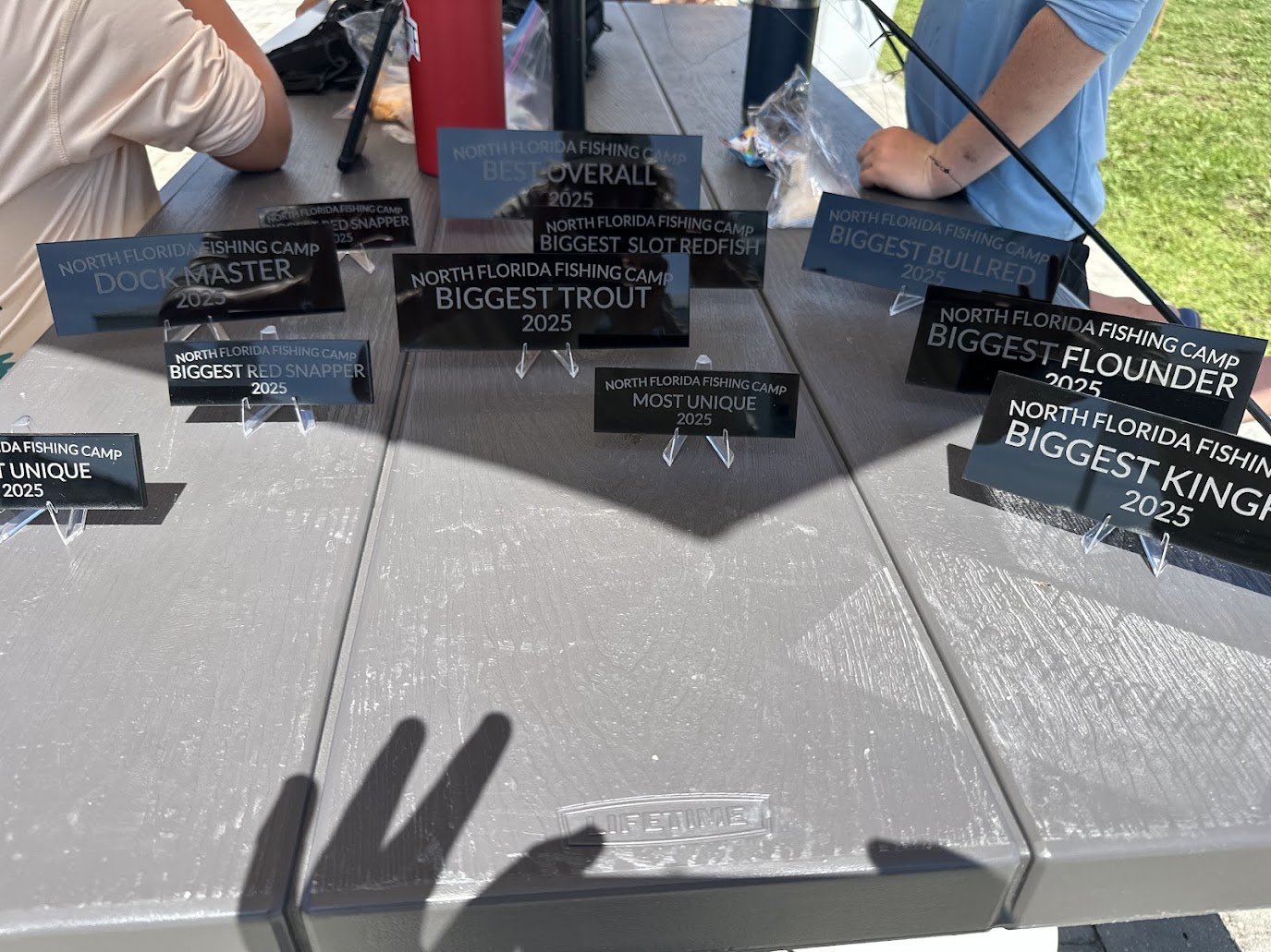 North Florida Fishing Camp award plaques lined up on a table: Biggest Trout, Dock Master, Most Unique and more