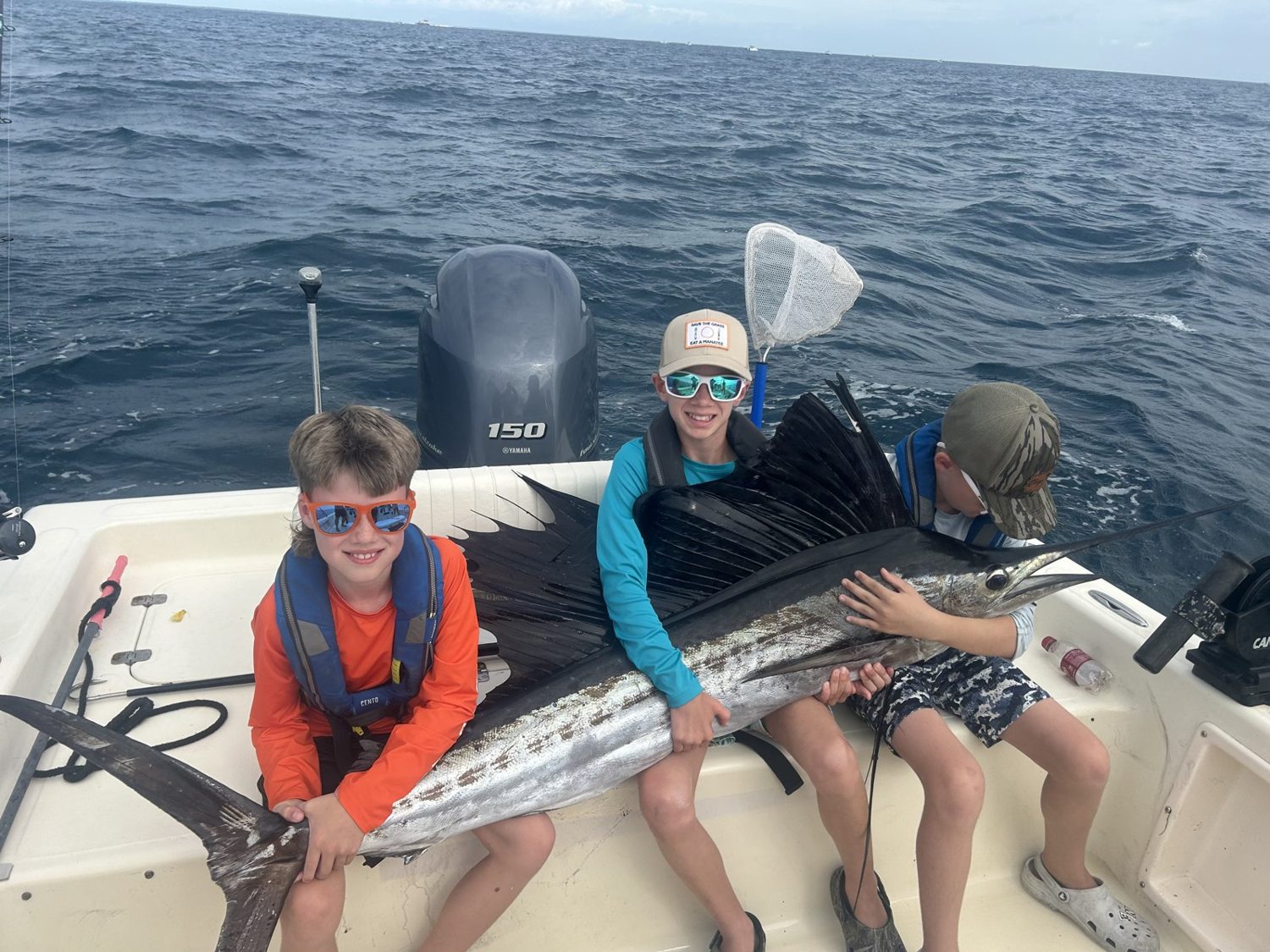 Two advanced campers holding a sailfish on the boat offshore