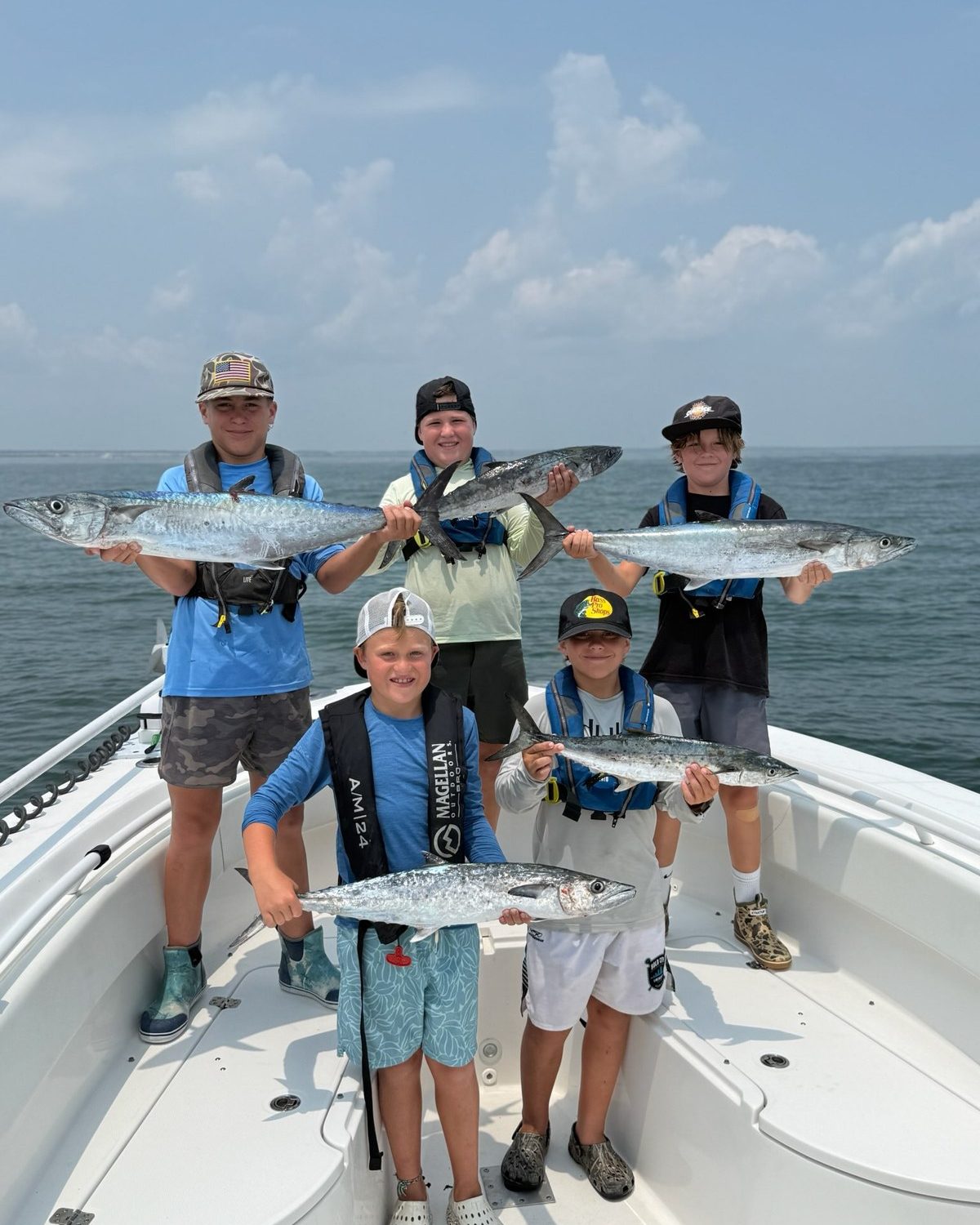 Advanced campers on the boat each holding a fish
