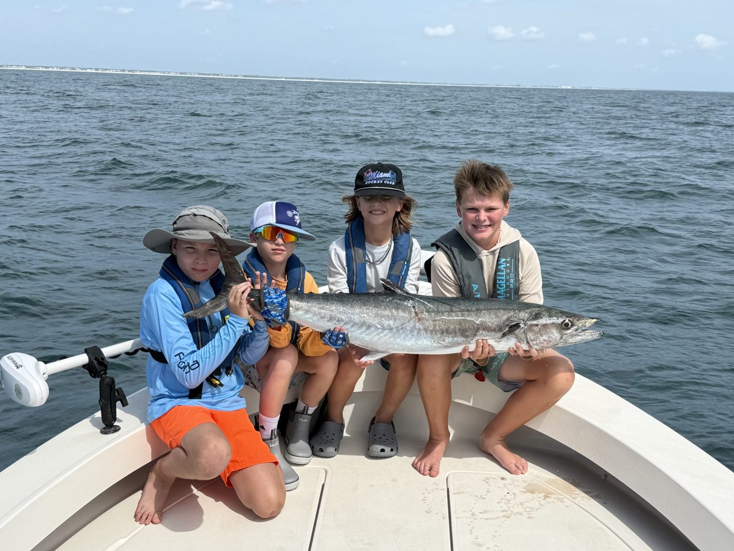 Four advanced campers holding a kingfish on the charter boat