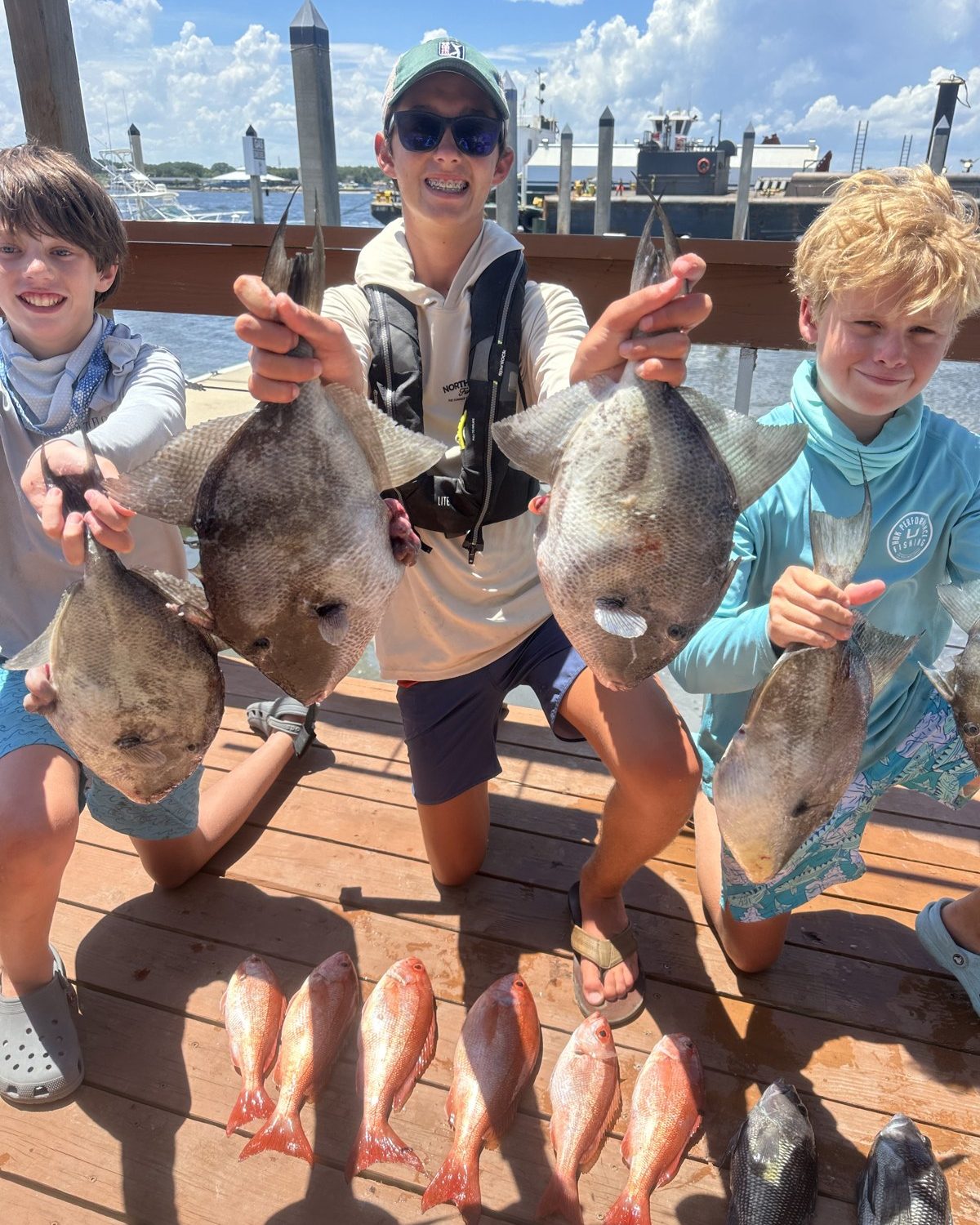 Three advanced campers with triggerfish and snapper on the dock