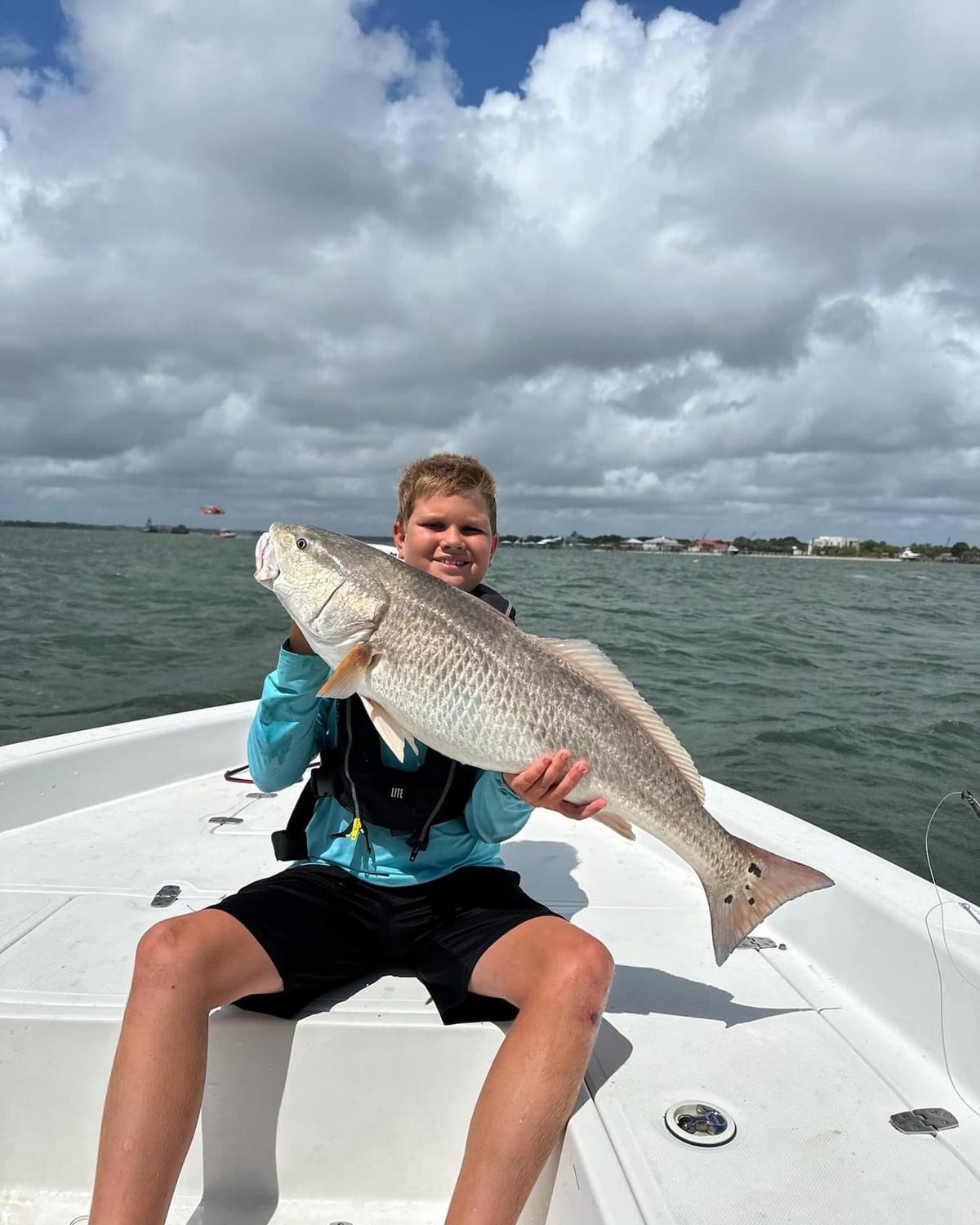 Camper on the bow holding a bull redfish
